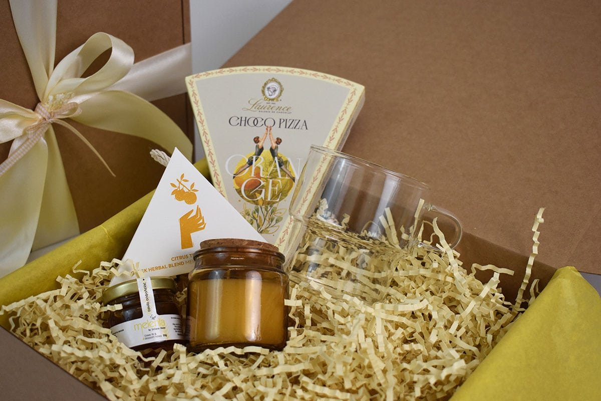 A Thoughtful Gesture — Κουτί με κίτρινη κορδέλα και επιλεγμένα συσκευασμένα προϊόντα.